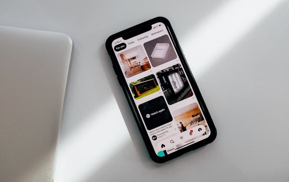 A phone on a desk showing a feed of posts