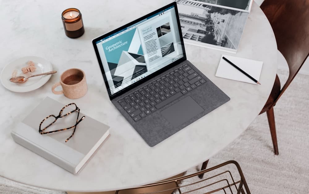 A quiet desk with a page layout on screen and a notebook alongside