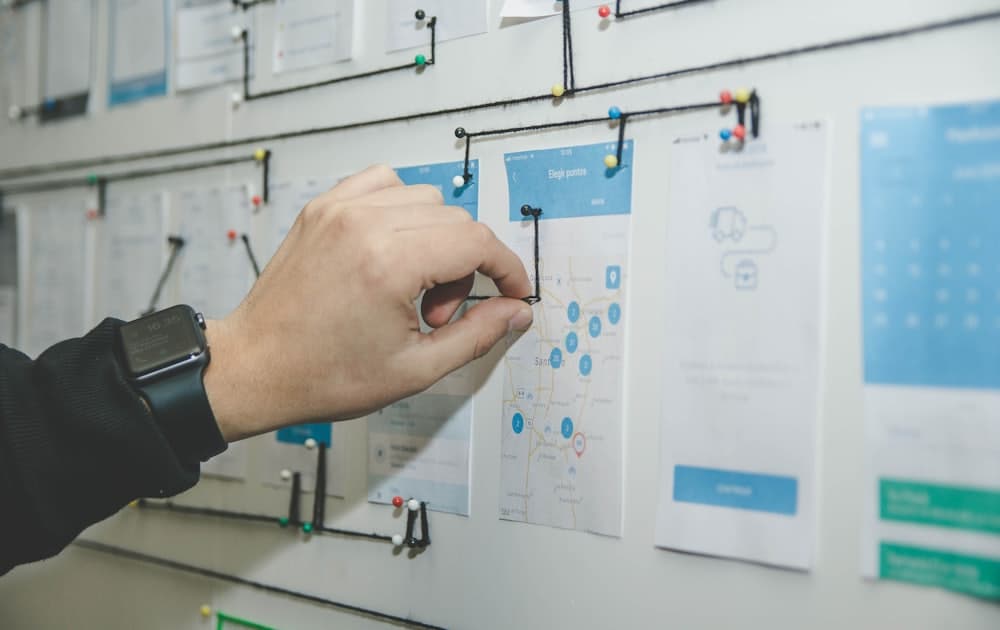 A hand pinning printed screens into a connected sequence on a wall