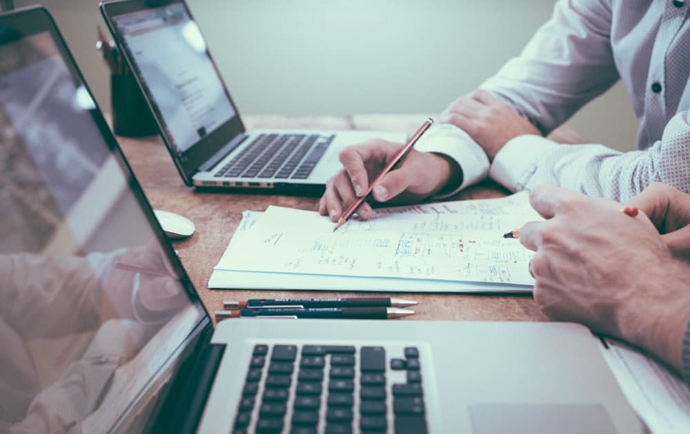 Two people marking up a printed plan at a desk with pencils